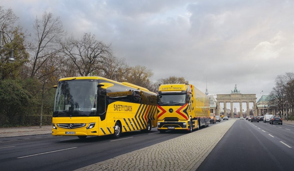 Mercedes-Benz autobuses de transporte de seguridad en la avenida con el monumento a la puerta de Brandeburgo en Berlín, Alemania.
