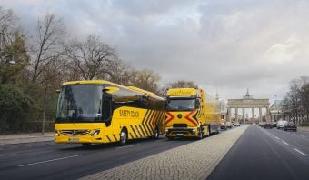 Mercedes-Benz autobuses de transporte de seguridad en la avenida con el monumento a la puerta de Brandeburgo en Berlín, Alemania.